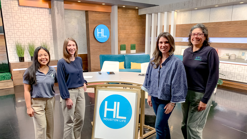 Four people pose in front of the host desk on the set of Houston Life.