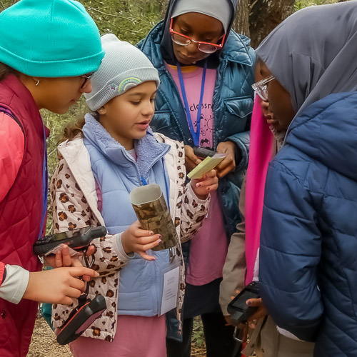 A group of young people gathered around a geoache.