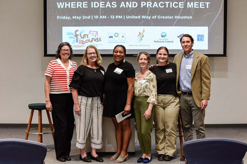 Group photo of six people standing in front of a presentation screen at the Confluence symposium.