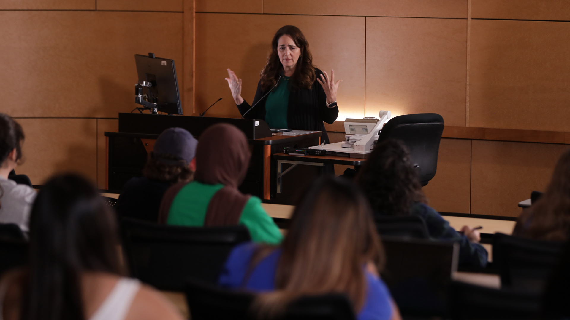 Photo of a faculty member lecturing at the front of a large classroom full of students