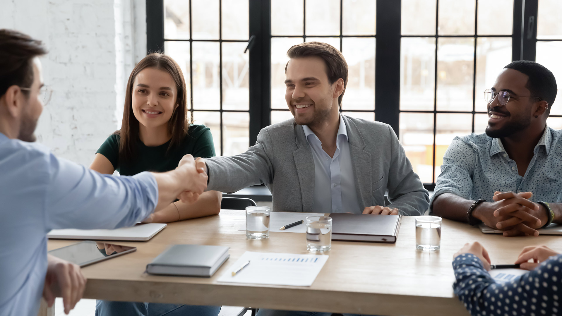 Photo of 4 people in a business setting around a conference table